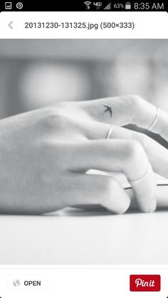 a person's hand with a tiny star tattoo on their left wrist is typing on a computer keyboard