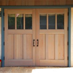 two wooden doors are open on the outside of a house in front of an american flag