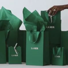 several green shopping bags are stacked on top of each other and being held by someone's hand