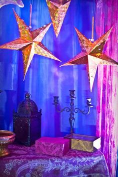 three paper stars hanging from the ceiling above a table with candles and other items on it