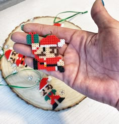 a hand holding an ornament in the shape of a santa clause on a piece of wood