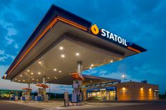 a gas station at dusk with the sign station on it's front and lights on