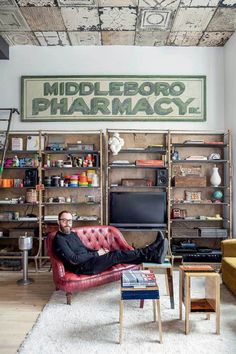 a man laying on top of a red couch in a living room