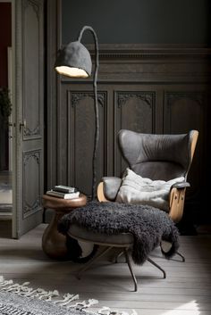 a living room with a chair, ottoman and lamp