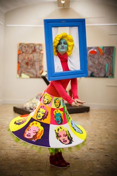 a woman in a colorful dress holding up a picture frame