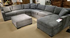 a large sectional couch and ottoman in a store