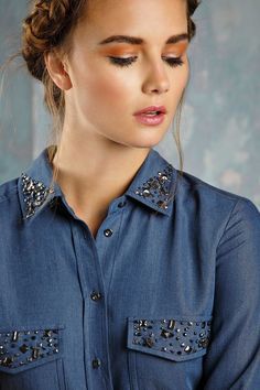 a woman wearing a blue shirt with silver sequins on the collar and cuffs