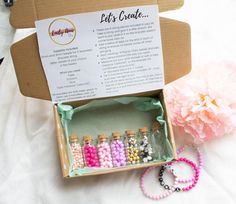 a box filled with lots of beads next to a pink flower on top of a bed