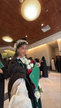 a woman in a graduation gown holding flowers