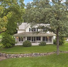 a large white house sitting in the middle of a lush green field next to a tree