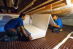 two men in blue shirts are working on an under construction area with metal grates