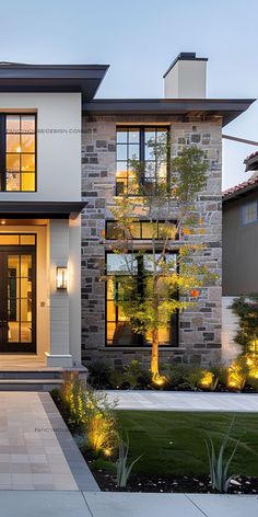 a modern house is lit up at night with lights on the front and side windows