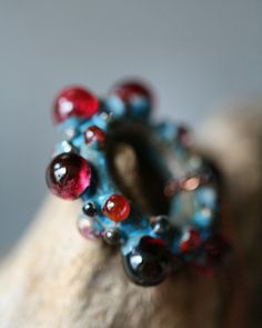 a close up view of a ring with red, blue and black beads on it