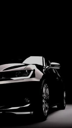 a black and white photo of a sports car in the dark with its hood up