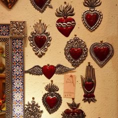 there are many heart shaped brooches hanging on the wall next to a mirror