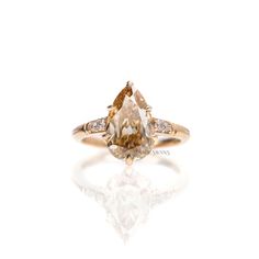 an orange and white diamond ring with diamonds around it's sidestone, set in yellow gold