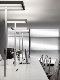 an empty conference room with chairs and desks in front of the window that has blinds on it