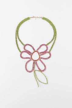 a necklace with pink and green beads hanging from it's center, in front of a white background