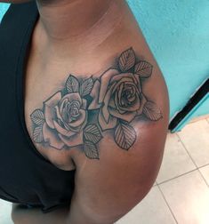 a close up of a woman's shoulder with roses on it and leaves in the middle