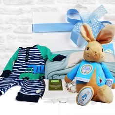 a stuffed rabbit sitting on top of a bed next to a blue and white blanket