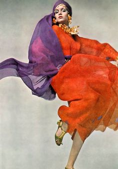 a woman in an orange and purple dress is flying through the air