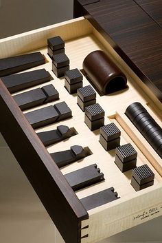 an assortment of wooden objects are displayed in a box on a table with other items