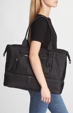 Stay organized with this versatile duffle bag featuring two interior compartments with a quick top zipper that makes it ideal for long weekends and work trips. This bag includes Tumi Tracer®, an exclusive, complimentary program that helps reunite lost or stolen bags with their rightful owners using a one-of-a-kind 20-digit number affixed to the bag Top carry handle; removable, adjustable crossbody strap Quick-access phone pocket; media pocket; water-resistant water bottle pocket; leather card po Elegant Large Capacity Duffle Bag For On-the-go, Functional Tote Travel Bag For Business Trips, Elegant Large Capacity Duffle Bag For Trip, Modern Tote Duffle Bag For Business Trips, Versatile Large Capacity Duffle Bag For Business Trips, Modern Gym Bag For Everyday Use, Modern Travel Bag With Zipper Pocket For Trips, Versatile Duffle Bag For Business Trips, Elegant Black Travel Bag For Trips