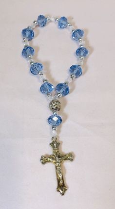 6” Rosary Overflowing Blue-Transparent Multifaceted Glass Beads and Crucifix This beautiful 6-inch bracelet is perfect for any occasion, whether it's Mother's Day, Christmas, birthdays, Valentine's Day, or Confirmation/Communion. The bracelet features 11 stunning blue and multicolored glass beads in a round shape, each measuring .375 inches in width, and one metal bead. The 11 blue beads are multifaceted, adding an extra touch of elegance. The bracelet also has a charming crucifix as a centerpiece, to complete the religious theme. It is held all together by elastic material for a comfortable fit making it easy to slip-on and pull-off. This item is perfect for those who love religious-themed jewelry and makes a great gift. Rosary stretch bracelet, with blue main beads with silver beads in b Rosary Bracelet Diy, Diy Rosary Bracelet, Diy Rosary Necklace, Rosary Ideas, Diy Rosary, Beautiful Rosaries, Catholic Rosary Bracelet, Anglican Rosary, Prayer Jewelry