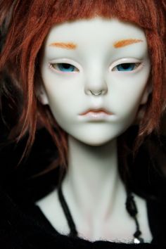 a doll with red hair and blue eyes wearing a black shirt is posed for the camera