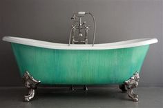 an old fashioned claw foot bathtub with green paint on the tub and chrome faucet