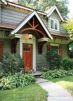 a small house with green siding and red trim on the front door is shown in this photo