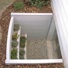 an open bathtub sitting on top of a gravel covered ground next to a white wall