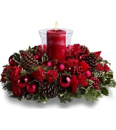 a red candle surrounded by pine cones and poinsettis