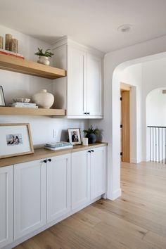 an empty kitchen with white cabinets and wood flooring is seen in this image from the hallway