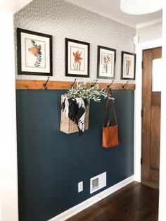 a blue wall with three pictures hanging on it's side and two purses hanging from the hooks