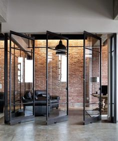 an open room with glass walls and black leather furniture in the center, surrounded by brick walls