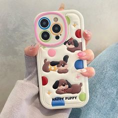 a woman holding a phone case with cartoon dogs on the front and bottom, while she's sitting down