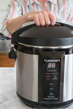 a person holding the lid on an electric pressure cooker