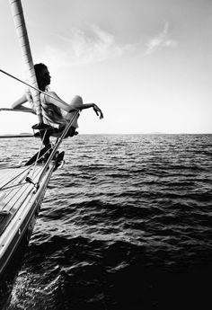 a person on a sailboat in the water with their arms out and feet up