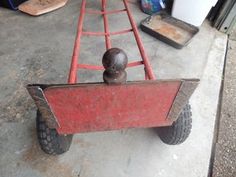 an old red wagon with wheels is sitting on the ground next to some other items