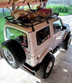 a white jeep with luggage on top parked under an awning in a driveway area