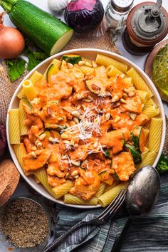 a bowl filled with pasta and sauce surrounded by other ingredients on top of a table