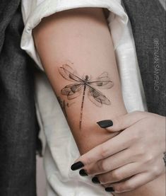 a woman's arm with a dragonfly tattoo on it