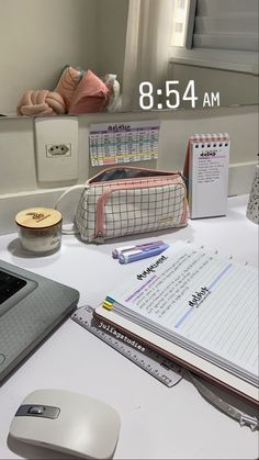 a laptop computer sitting on top of a white desk next to a pile of books