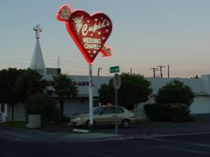 a heart shaped neon sign on the side of a building