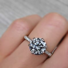 a woman's hand with a diamond ring on top of her finger and an engagement band