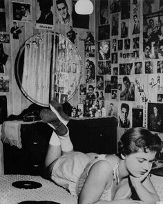 a young woman laying on her bed reading a book and looking at herself in the mirror