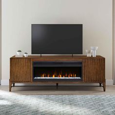 an entertainment center with a fireplace and television on it in front of a white wall