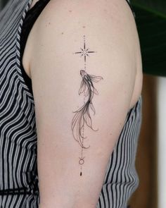 a woman's back shoulder with a fish tattoo on the left side of her arm