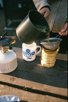 a person pours tea from a pot into a cup